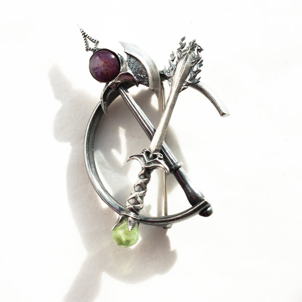 cutting through sterling silver brroch with a star ruby and peridot in natural light