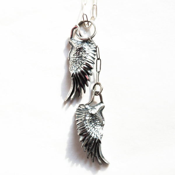 closeup of the wings silver necklace charms in a different light