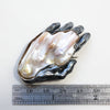 A baroque pearl as the back of a blackened silver left hand brooch. Measure