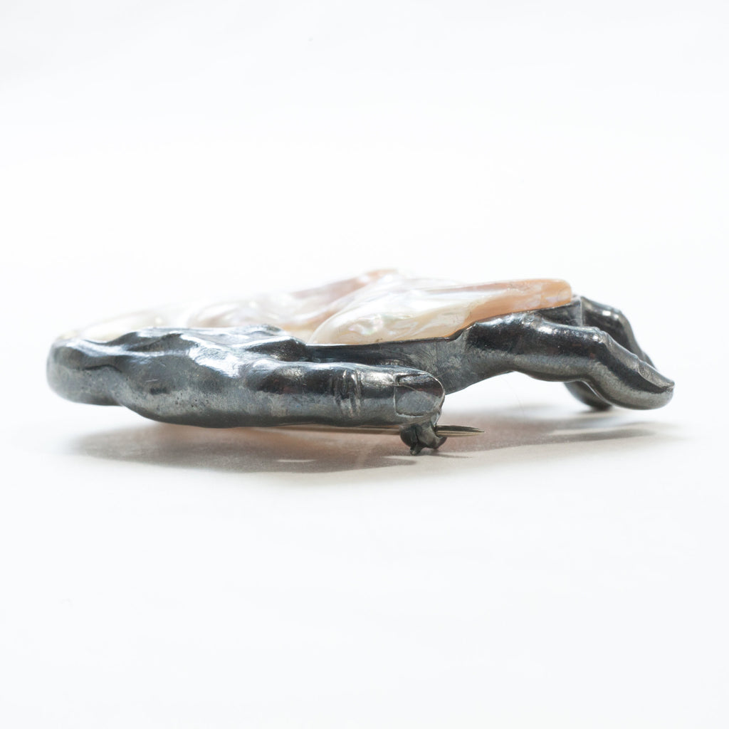 A baroque pearl as the back of a blackened silver left hand brooch. view from the thumb side