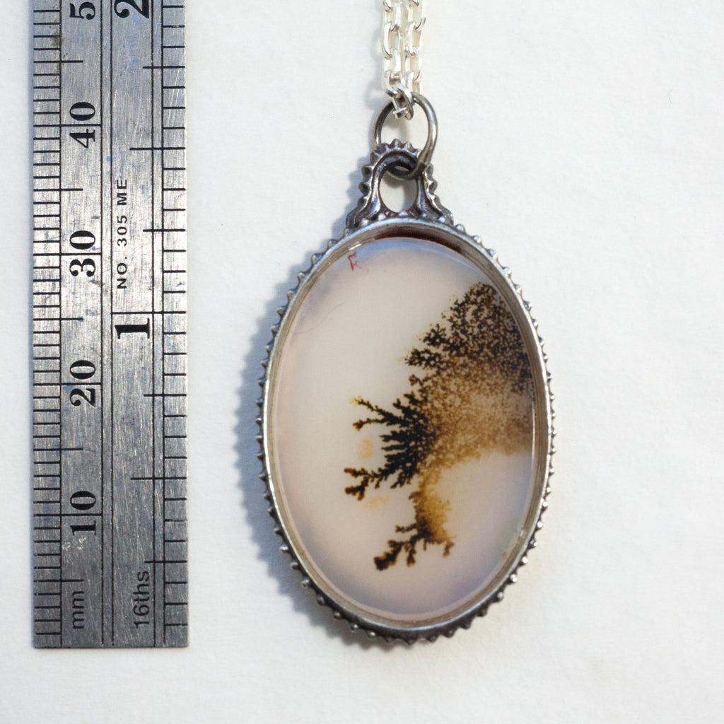 Lace-like dendritic agate in a victorian style silver frame on a silver chain. Measure