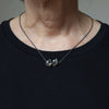 double bird silver necklace with a sapphire eye is shown being worn.