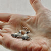 fin sterling silver earrings shown in the palm of a hand for size comparison