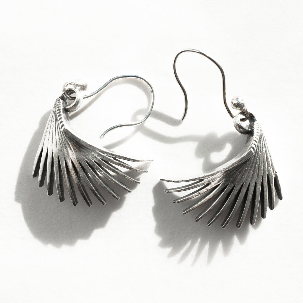 gently curving sterling silver fin earrings shown in a natural light