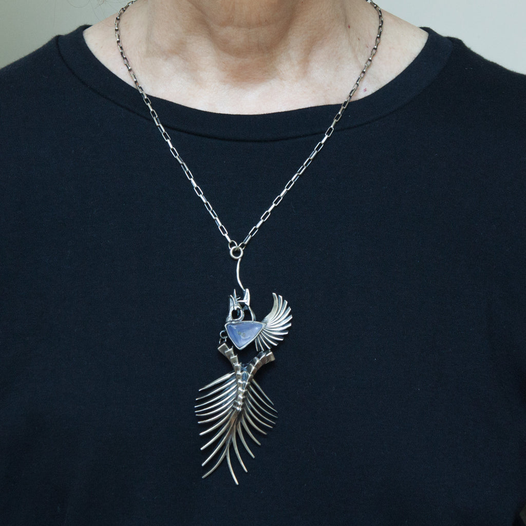 Sterling silver fishbones necklace with blue chalcedont shown being worn.