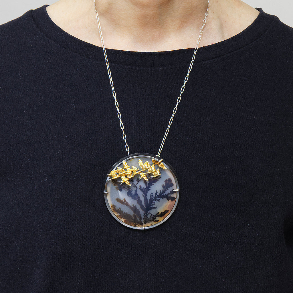 Round dendritic agate bush with golden swallows flying by. Brooch pendant. shown worn.