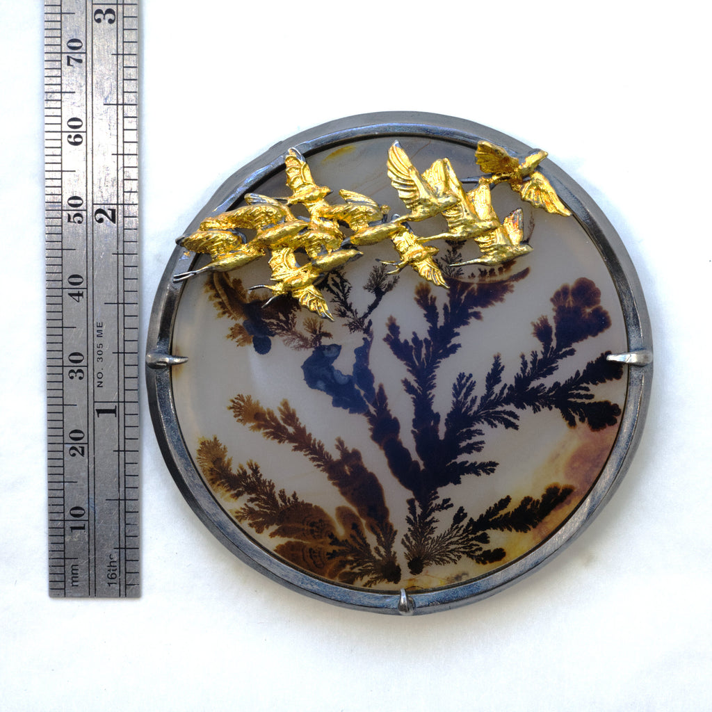 Round dendritic agate bush with golden swallows flying by. Brooch pendant. Front measure.