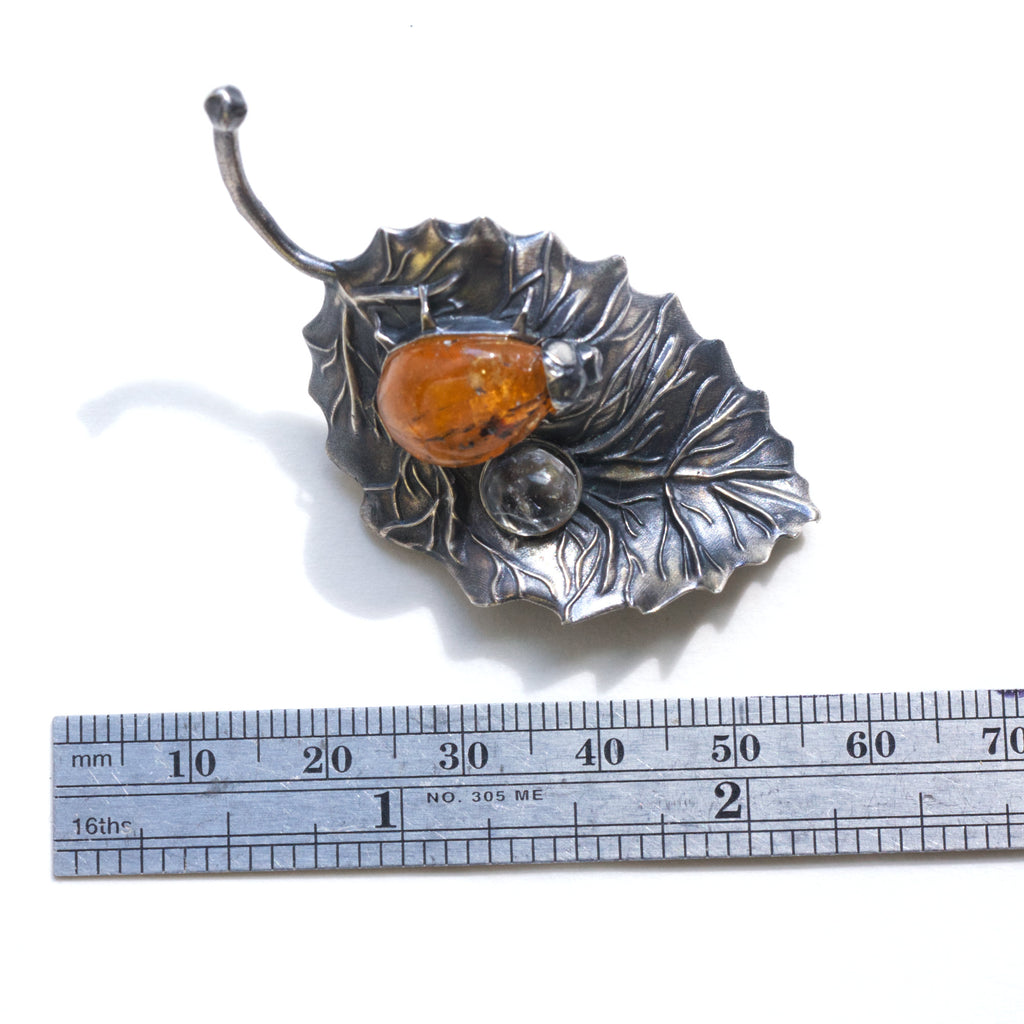 spessartite garnet ladybug on a sterling silver leaf blackened with liver of sulfur, and a topaz dewdrop. Measure