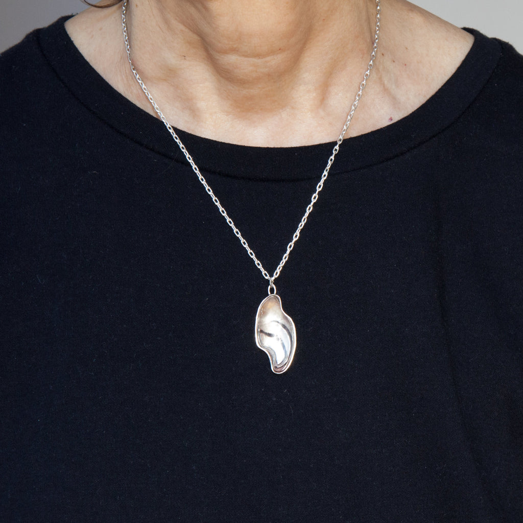 large carved quartz silver necklace with design on the back as worn