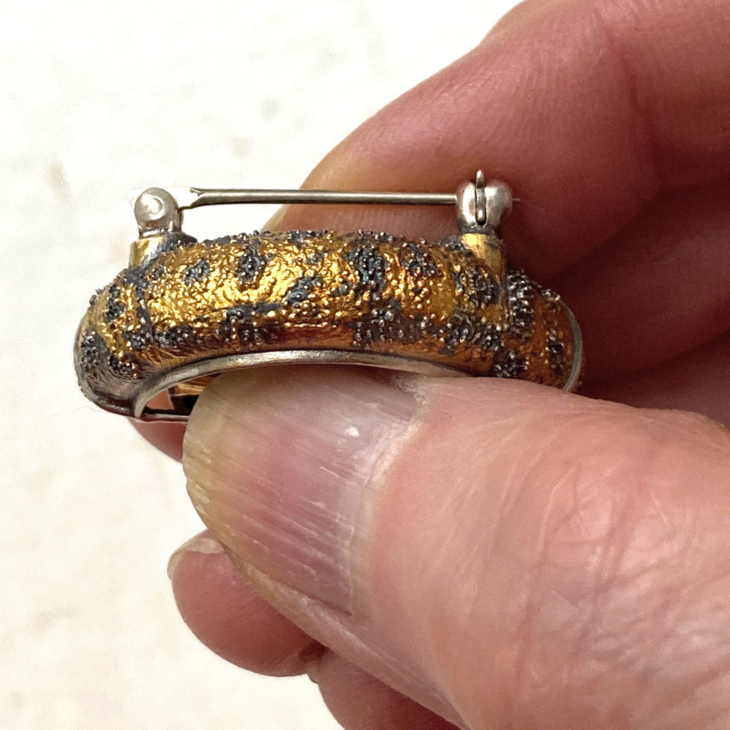 Lux fender brooch pendant with a pink spinel , blackened ssilver. 24k gold fused using keum boo process. The hubcap spins.Top