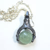 A dragon holding a prehnite sphere like he just caught it. Blackened silver, with a silver chain, back with chain