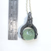 A dragon holding a prehnite sphere like he just caught it. Blackened silver, with a silver chain, measure