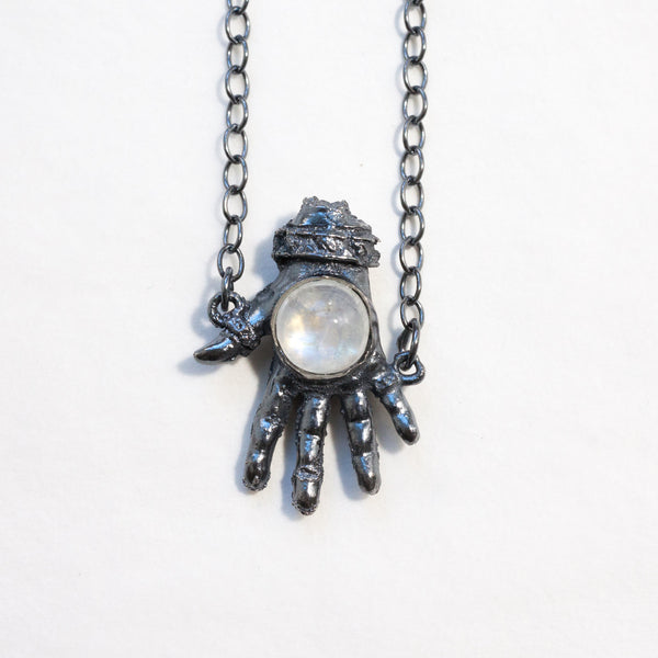 blackened silver with a raindow moonstone, this open giving hand has been damaged by outside circumstances. Front