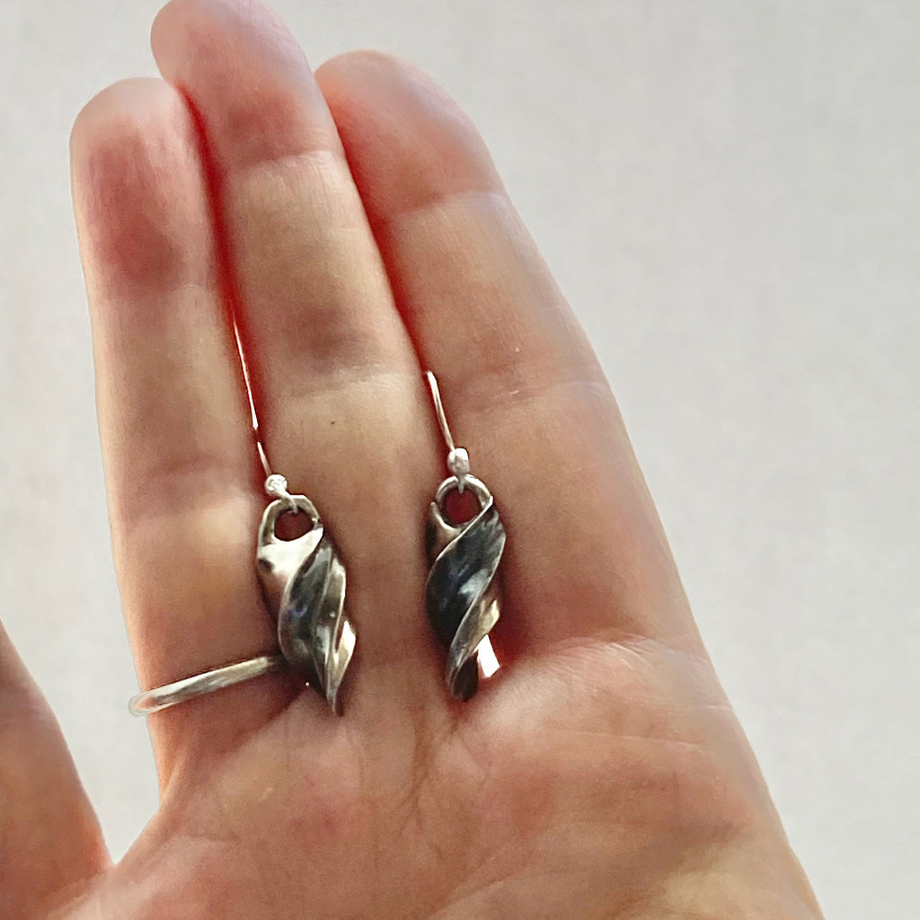 twirl sterlinng silver earrings shown in a hand for size comparison