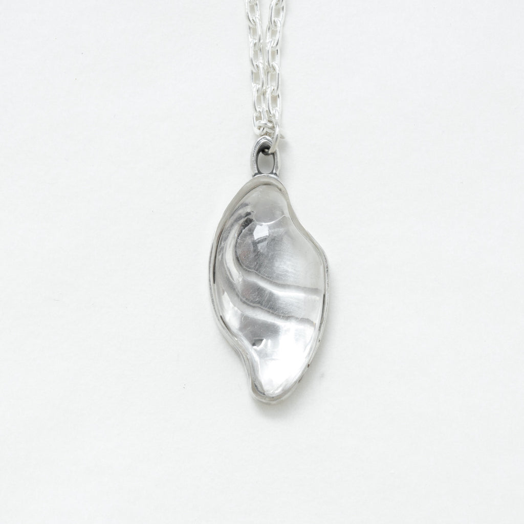 small carved quartz silver necklace with design on the back. front view