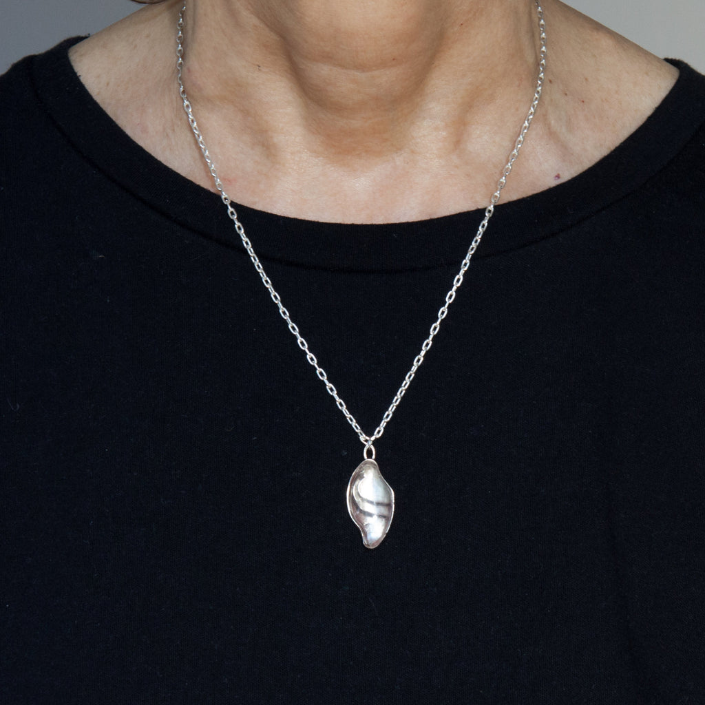 small carved quartz silver necklace with design on the back as worn