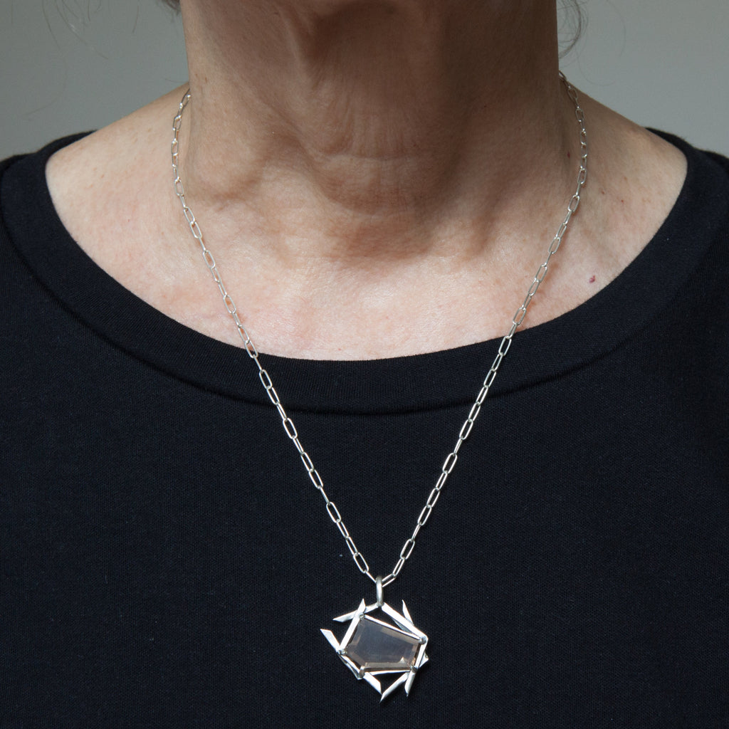 quartz pentagonal sterling silver pendant is shown being worn against a black top.