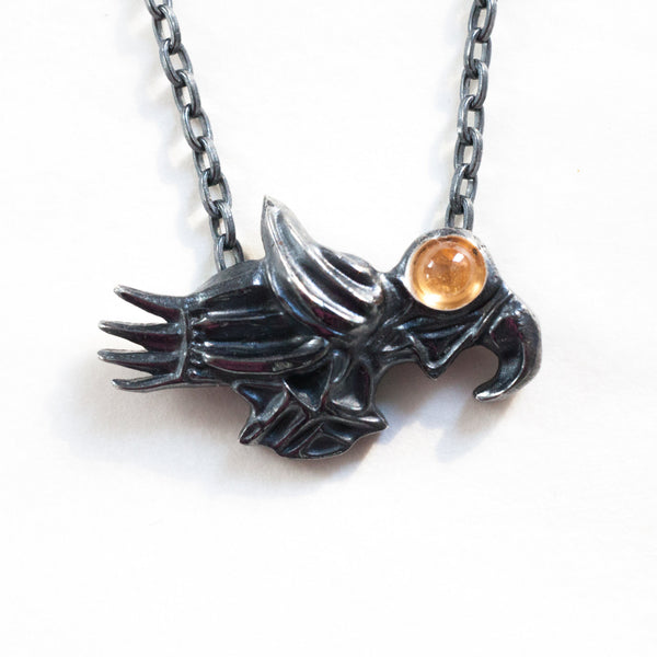 closeup of the soaring bird necklace with sessartite garnst and blackened silver in a different kind of light