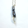 A white topaz with inclusions in a  blackened silver baby monster mount and 18" silver chain, side view