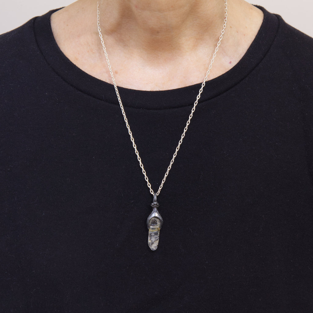 A white topaz with inclusions in a  blackened silver baby monster mount and 18" silver chain, as worn.