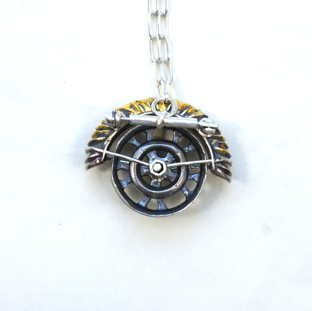 yaya fender brooch pendant. Blackened sterling silver, 24k gold foil applied using keum boo. Tthe hubcap spins. Back with chain,