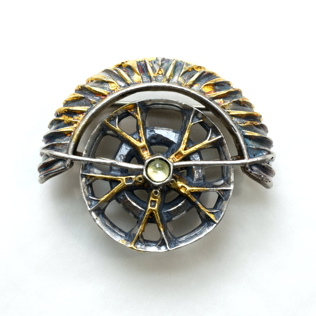 yaya fender brooch pendant. Blackened sterling silver, 24k gold foil applied using keum boo. The hubcap spins. front.