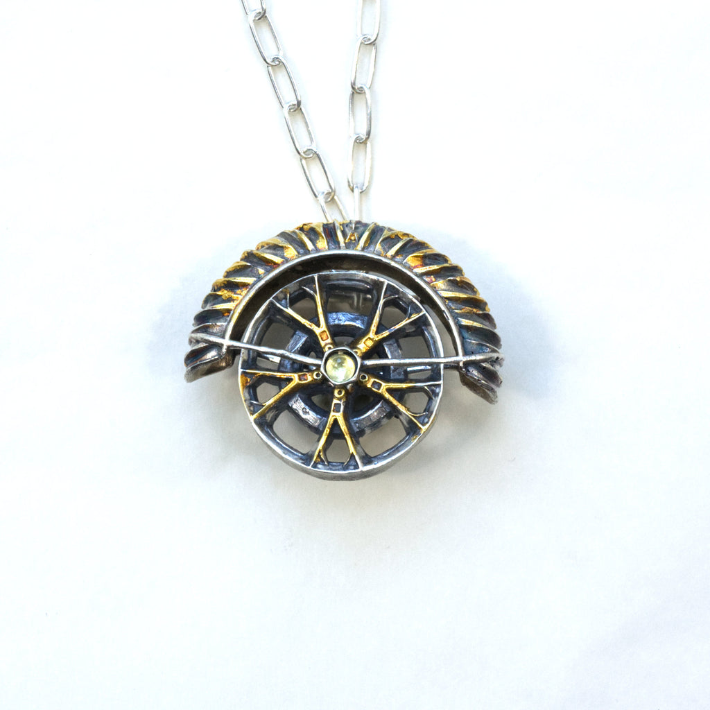 yaya fender brooch pendant. Blackened sterling silver, 24k gold foil applied using keum boo. Tthe hubcap spins. Front with chain