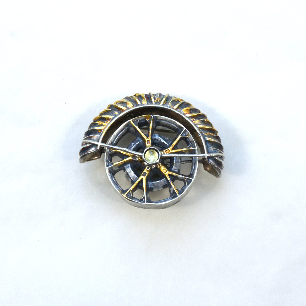 yaya fender brooch pendant. Blackened sterling silver, 24k gold foil applied using keum boo. Tthe hubcap spins. Front.