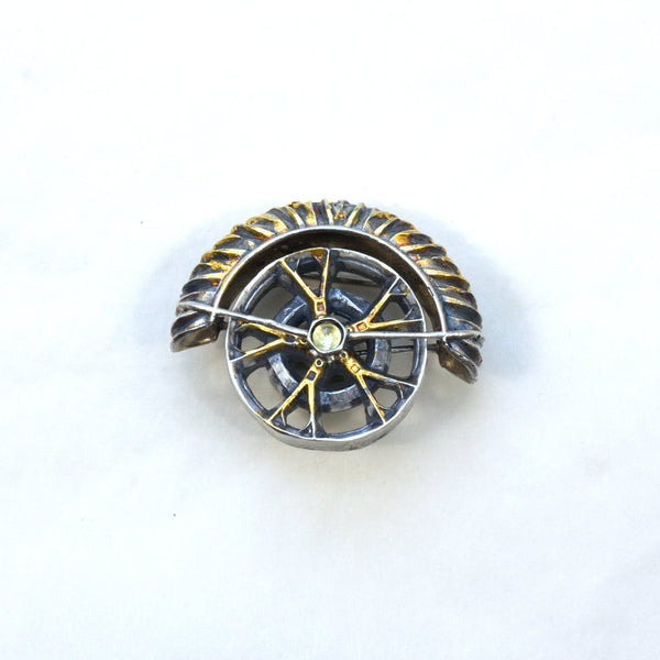 yaya fender brooch pendant. Blackened sterling silver, 24k gold foil applied using keum boo. Tthe hubcap spins. Front.