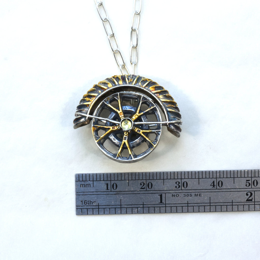 yaya fender brooch pendant. Blackened sterling silver, 24k gold foil applied using keum boo. Tthe hubcap spins. Measure.