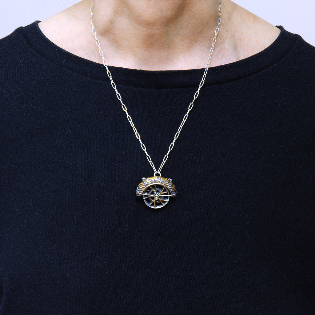 yaya fender brooch pendant. Blackened sterling silver, 24k gold foil applied using keum boo. Tthe hubcap spins. Worn.